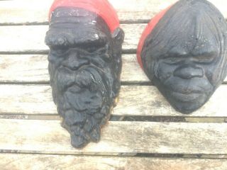 A Vintage Cast Iron Aboriginal Masks Of A Man & Woman Painted Black,  Red