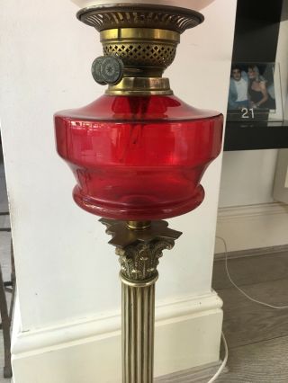 large oil lamp with blood red glass fount,  brass corinthian base and red shade 10