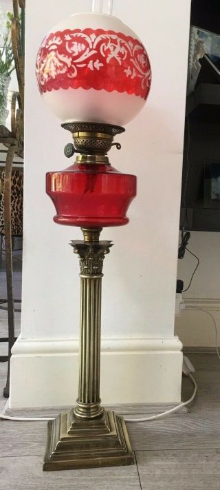 large oil lamp with blood red glass fount,  brass corinthian base and red shade 9