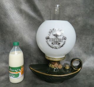 A Ceramic Genie Shaped Oil Lamp With Aladdins Oil Advertisement Shade